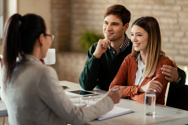 Young smiling couple having a meeting with financial advisor in the office.