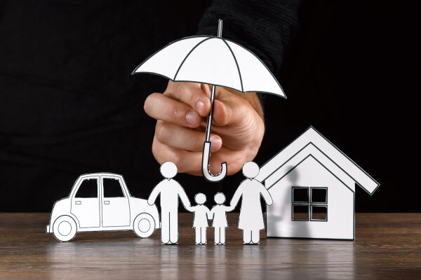 The concept of car insurance, a man covers a car with paper hands, close-up.